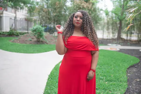 Andrea “Vocab” Sanderson in a red dress on a winding garden path